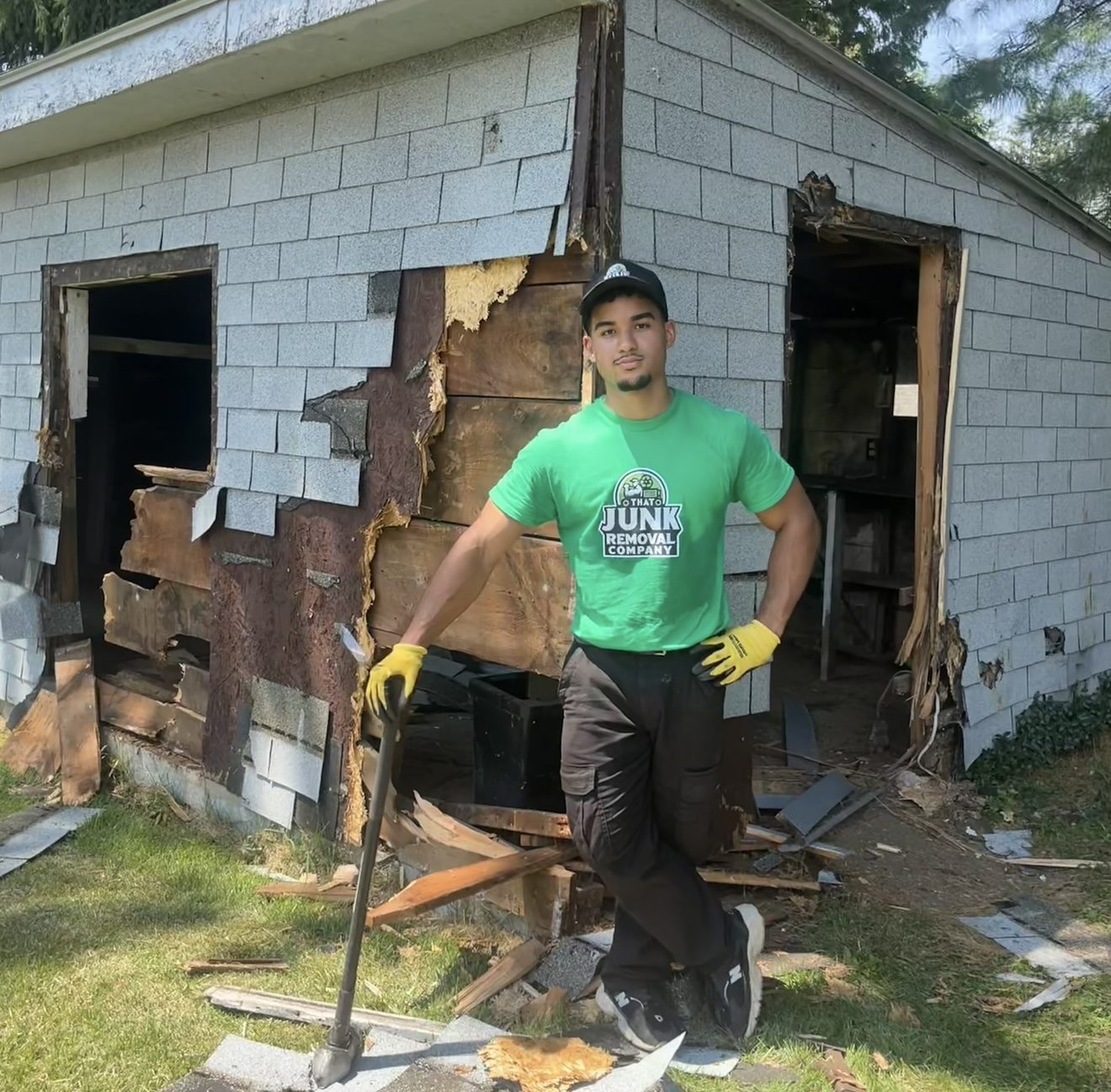 Crew member tearing down the wall of an old shed by hand